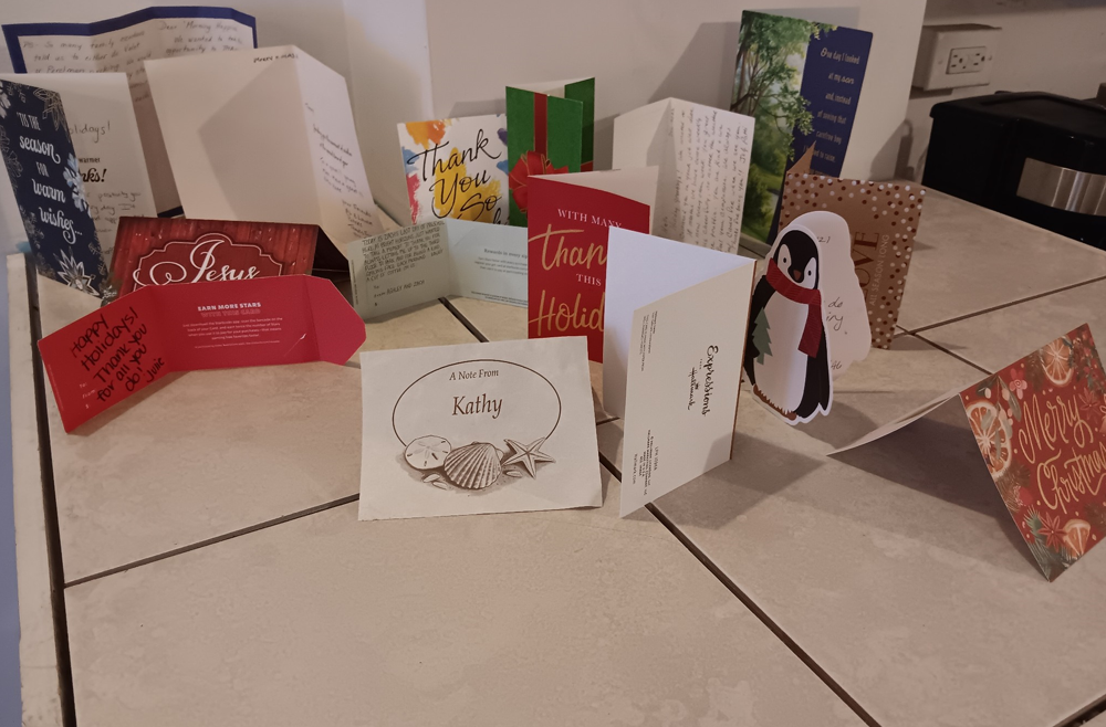 A row of holiday and thank you cards on a table.